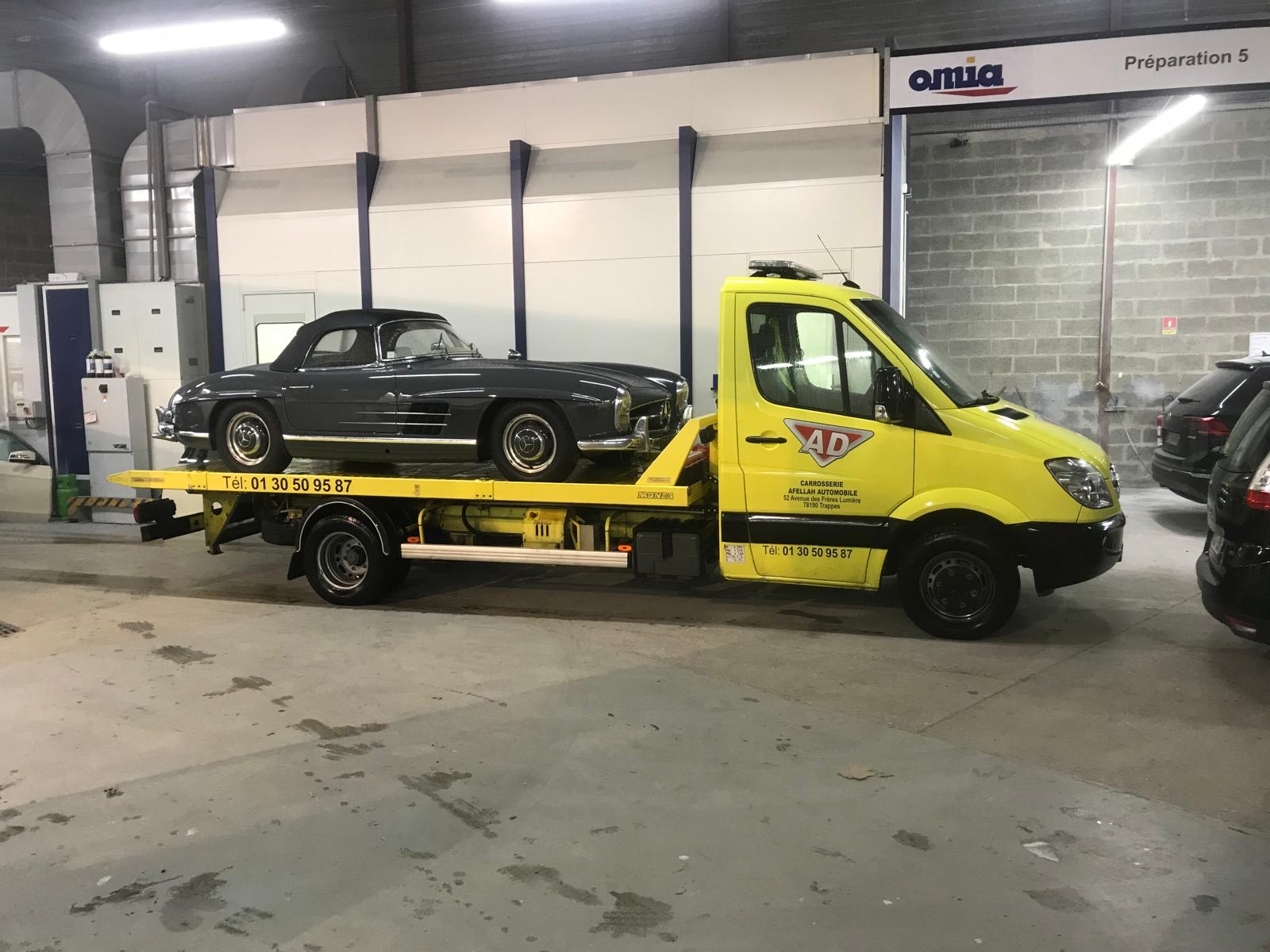 Camion plateau jaune AD d'Afellah Automobile transportant une voiture de collection dans l'atelier de Trappes